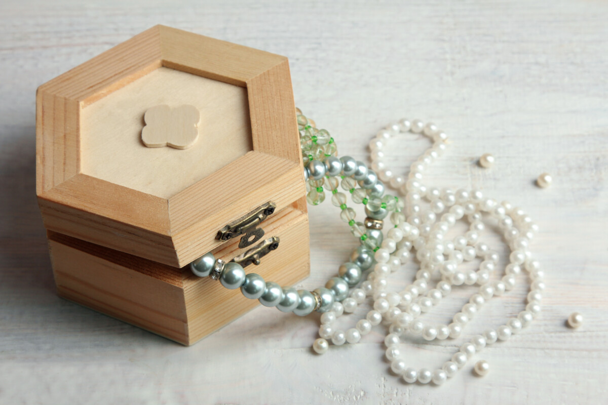 ajar wooden casket on wooden background with beads and jewels